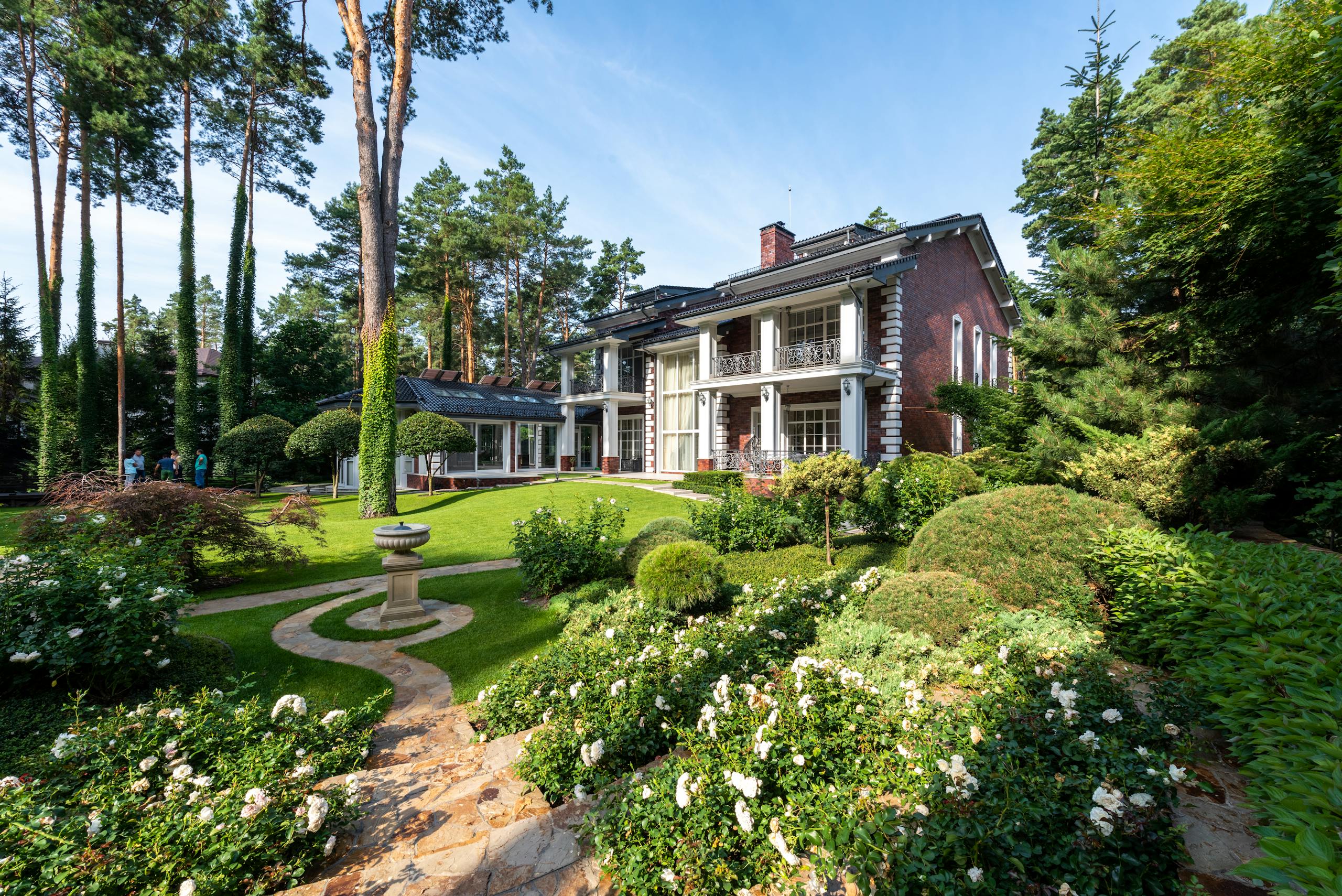 Beautiful luxury villa surrounded by manicured garden and lush landscaping on a sunny day.